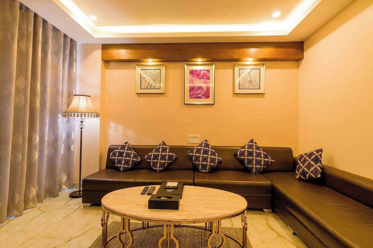 Un salon avec un canapé, une table basse ronde et une lampe. Trois tableaux encadrés sont accrochés au mur.