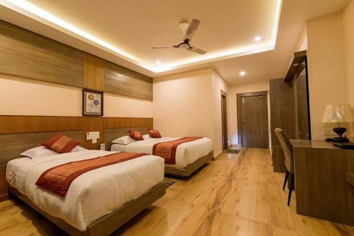 Une chambre d’hôtel avec deux lits, un bureau, une chaise et un ventilateur de plafond.