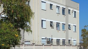 A multi-story building with a flat facade, white exterior, and barred windows.