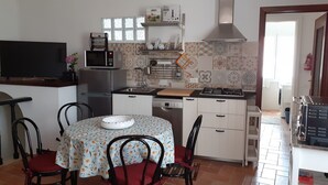 A compact kitchen with a dining area, equipped with a microwave, stove, and sink. - CasaRina Poggi - 360° Panoramic Terrace from the Mountains to the Sea and Relaxation in Imperia (Poggi)