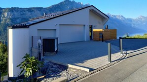 A modern house with a garage, a small garden, and a mountain view. - Apartment Panorama Walensee (Glarus Nord)