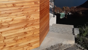 A modern building with a wooden facade and a view of a mountain and lake. - Apartment Panorama Walensee (Glarus Nord)