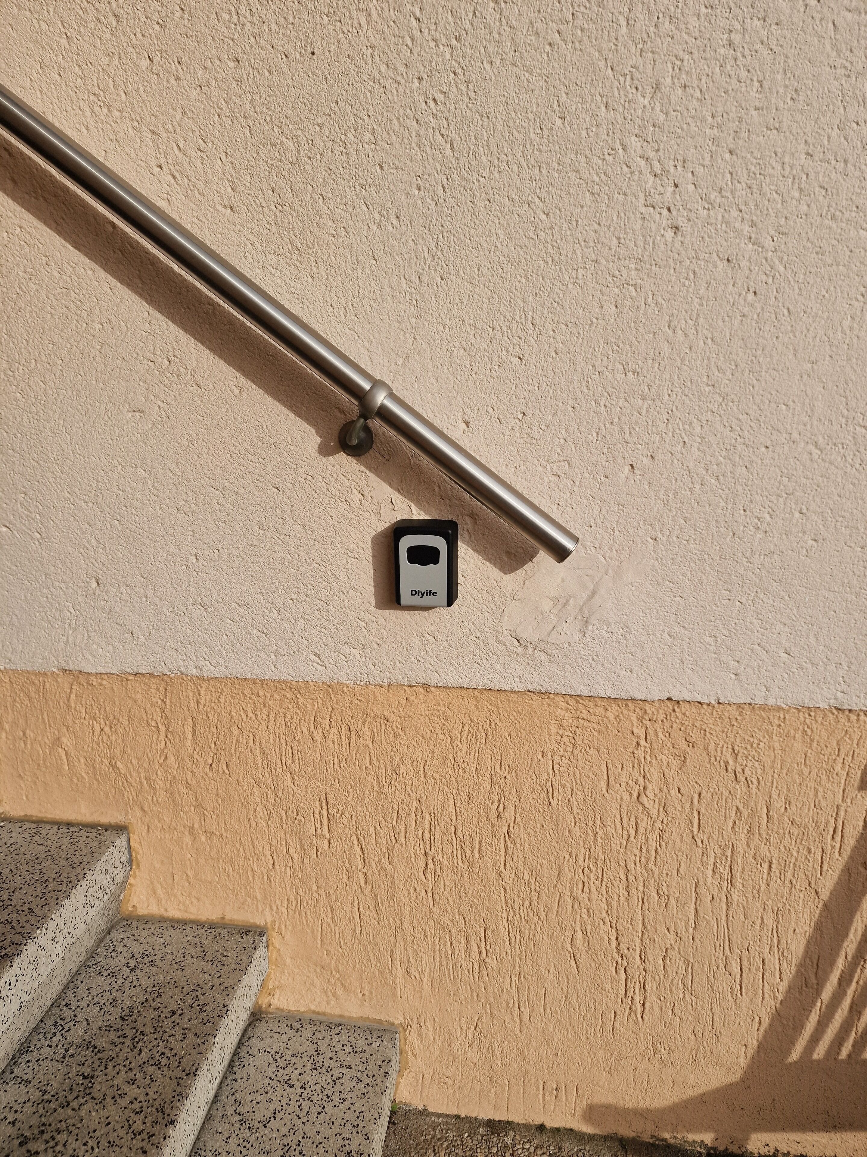 A metal handrail with a sensor labeled "Diylife" mounted on a textured wall.