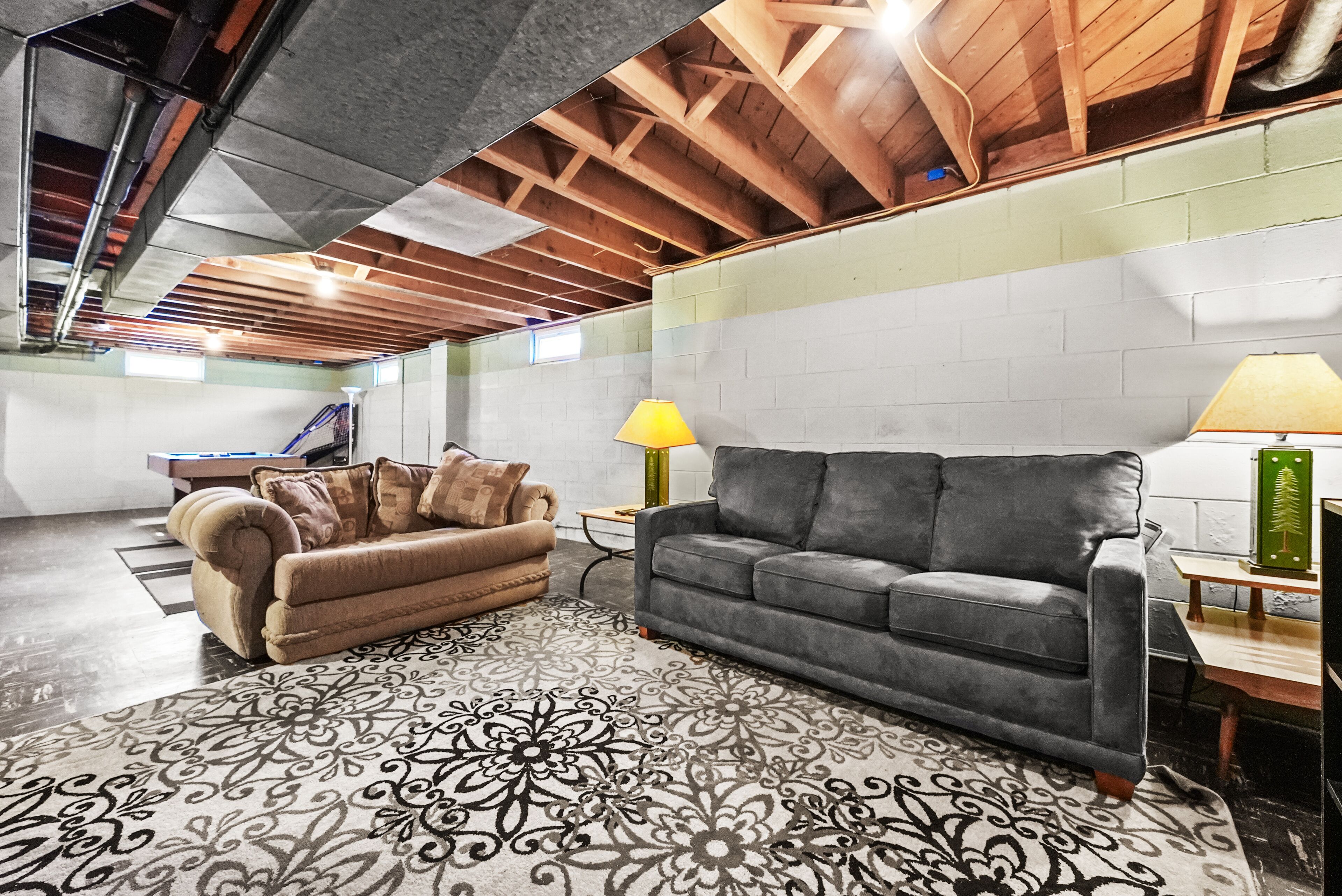 A spacious living room with two sofas, a patterned rug, and a wooden ceiling.