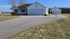 A single-story house with a garage and a small attached shed, surrounded by a grassy yard and a clear sky. - 3 bedroom, 2.5 bath home,  with 2 car garage, minutes from Frankenmuth.  (Birch Run)