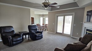 A living room with a ceiling fan, a fireplace, and a large sliding glass door leading to a patio. - 3 bedroom, 2.5 bath home,  with 2 car garage, minutes from Frankenmuth.  (Birch Run)