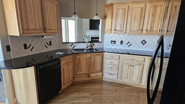A kitchen with wooden cabinets, a black countertop, and a tiled backsplash. - 3 bedroom, 2.5 bath home,  with 2 car garage, minutes from Frankenmuth.  (Birch Run)