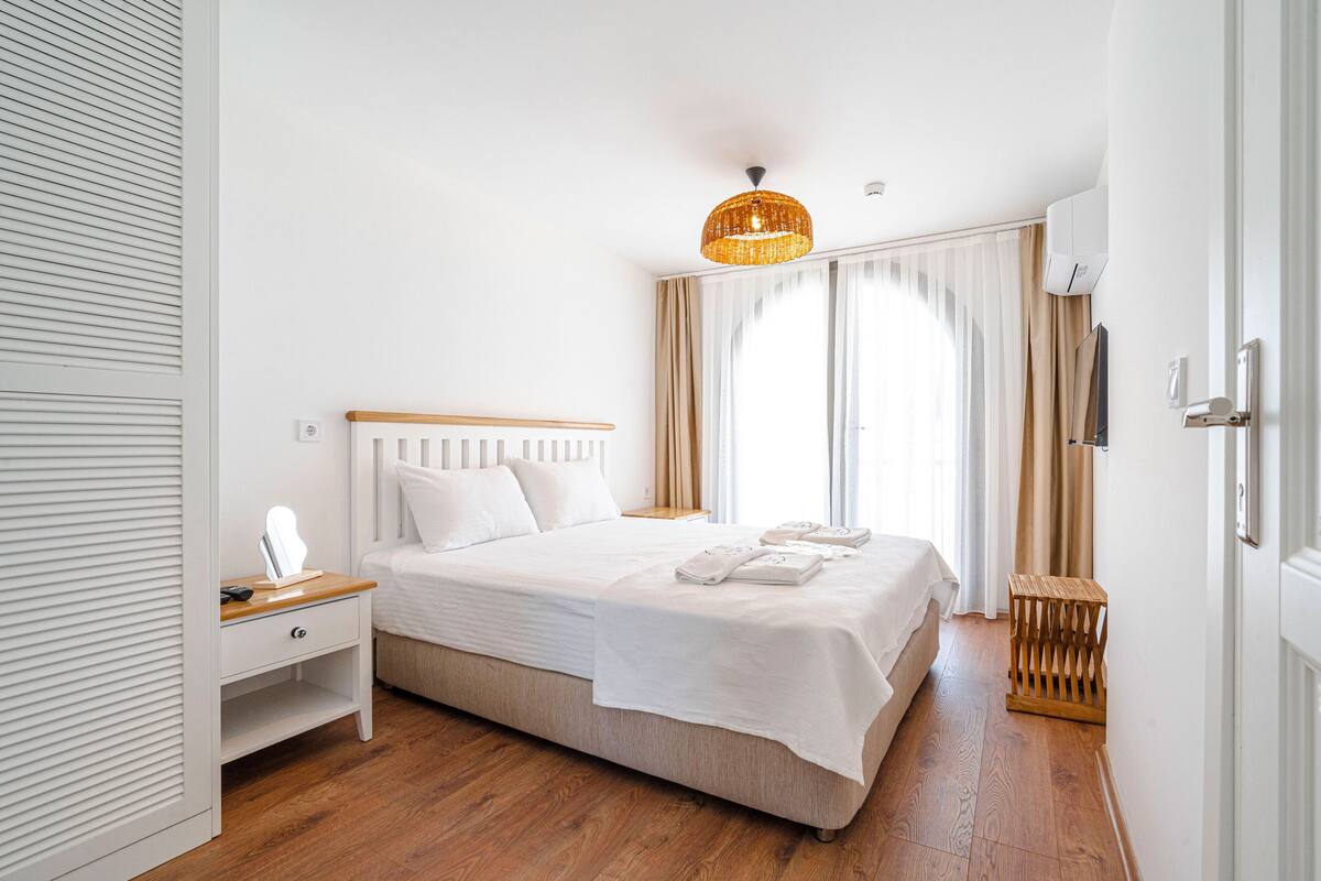 Ein ordentlich eingerichtetes Schlafzimmer mit Bett, Nachttisch und einer Hängelampe.