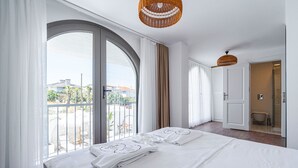 Quarto de hotel com uma cama grande, varanda com vista e área de chuveiro.