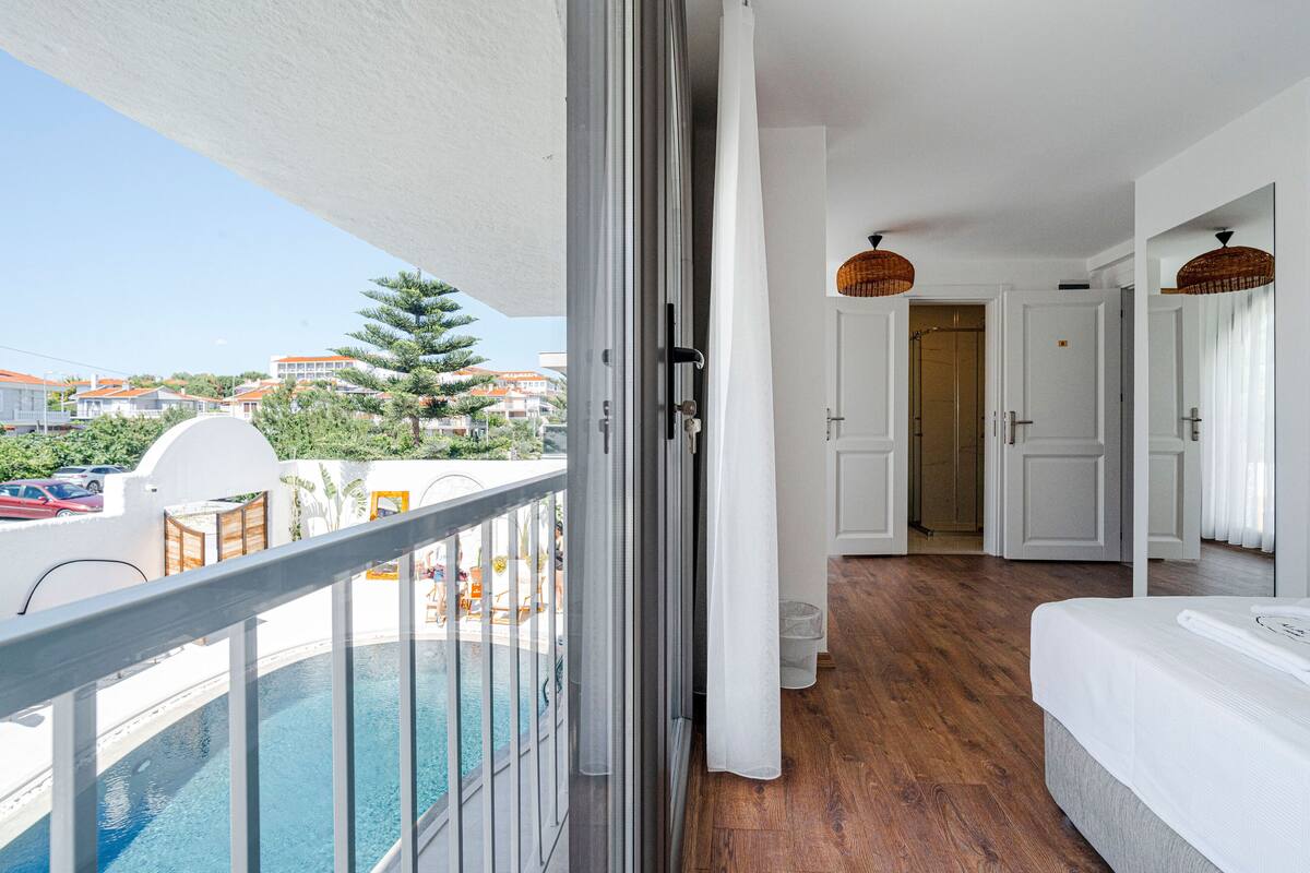 Ein Balkon mit Pool, ein Schlafzimmer mit Bett und eine Tür zu einem weiteren Raum.