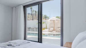 Quarto de hotel com cama, banheiro e vista para a área da piscina externa.