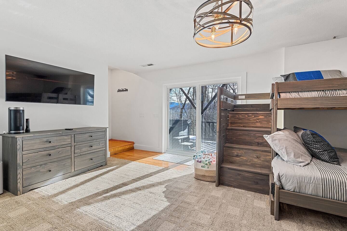 Quarto moderno com cama de beliche, espelho grande, cômoda de madeira e vista para o exterior.