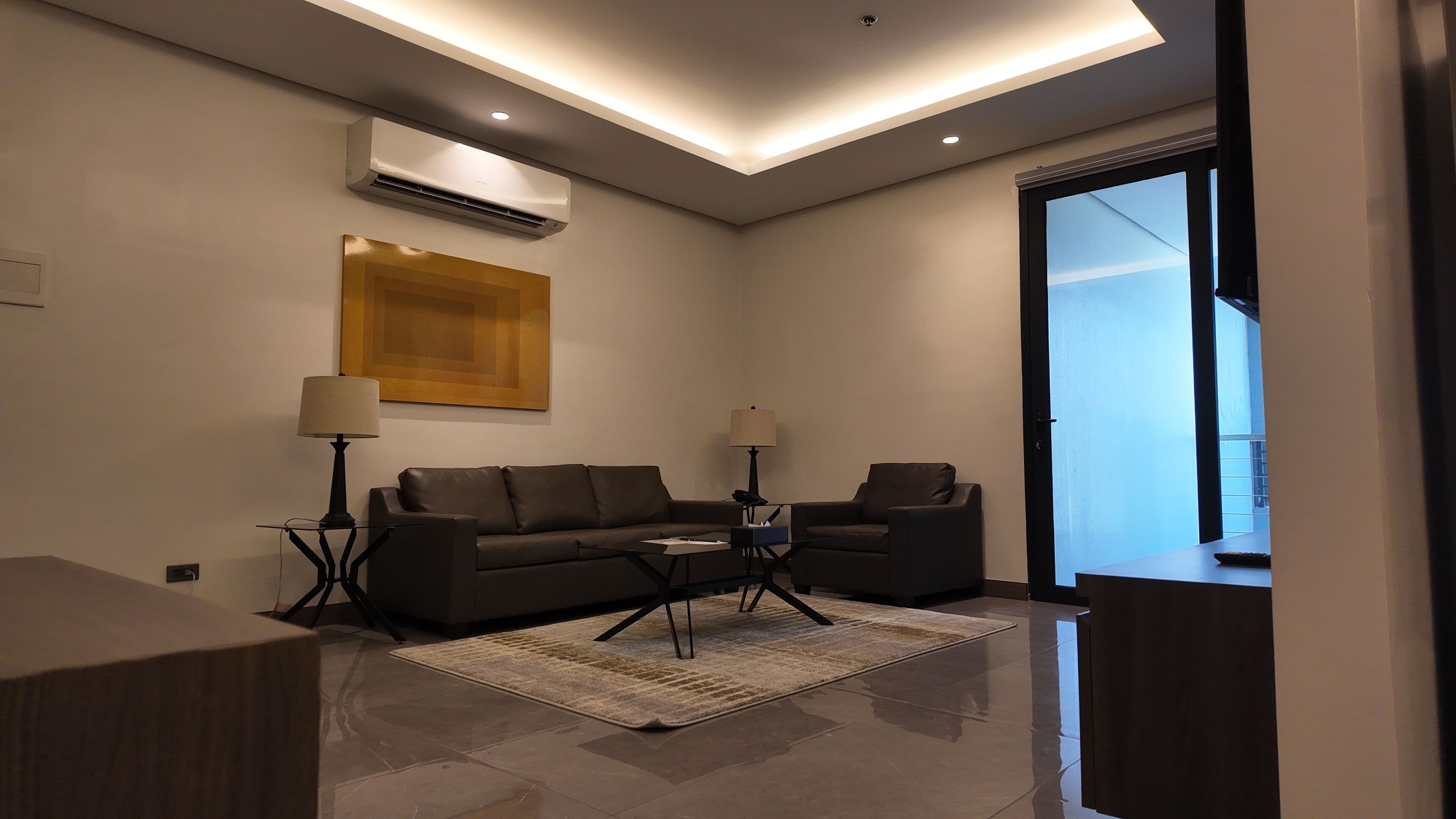 Een moderne woonkamer met een zithoek, twee bijzettafels, een salontafel en een wandairconditioning.
