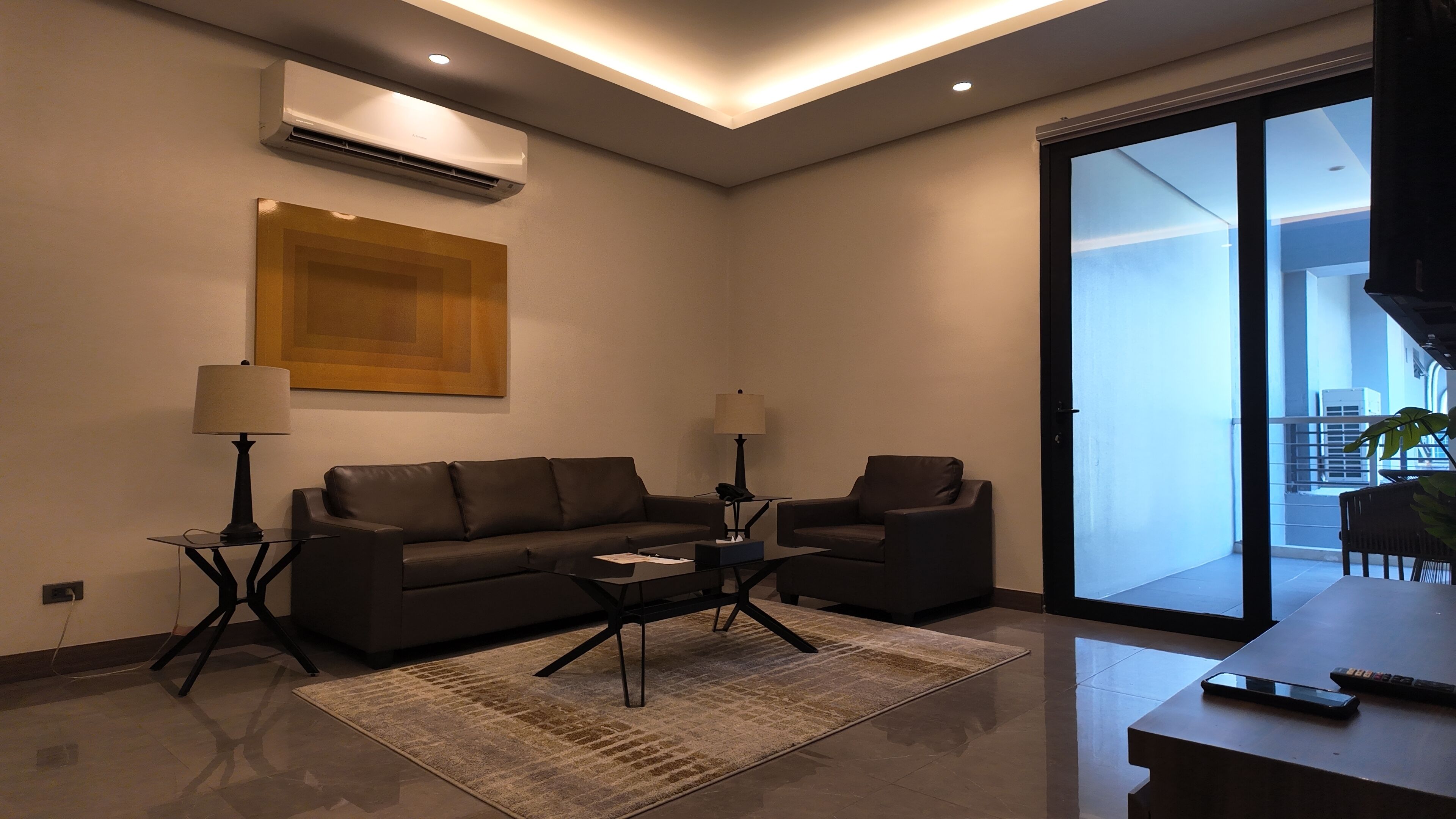 Ein modernes Wohnzimmer mit einer Couch, zwei Sesseln, einem Couchtisch und einer Lampe.