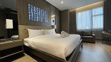 Une chambre d’hôtel moderne dotée d’un grand lit, d’un canapé, d’un bureau et d’une grande fenêtre avec des rideaux.
