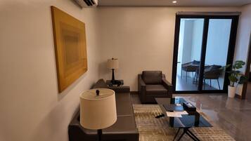 Un salon moderne avec un canapé, une table basse, une lampe et une vue sur le balcon extérieur.