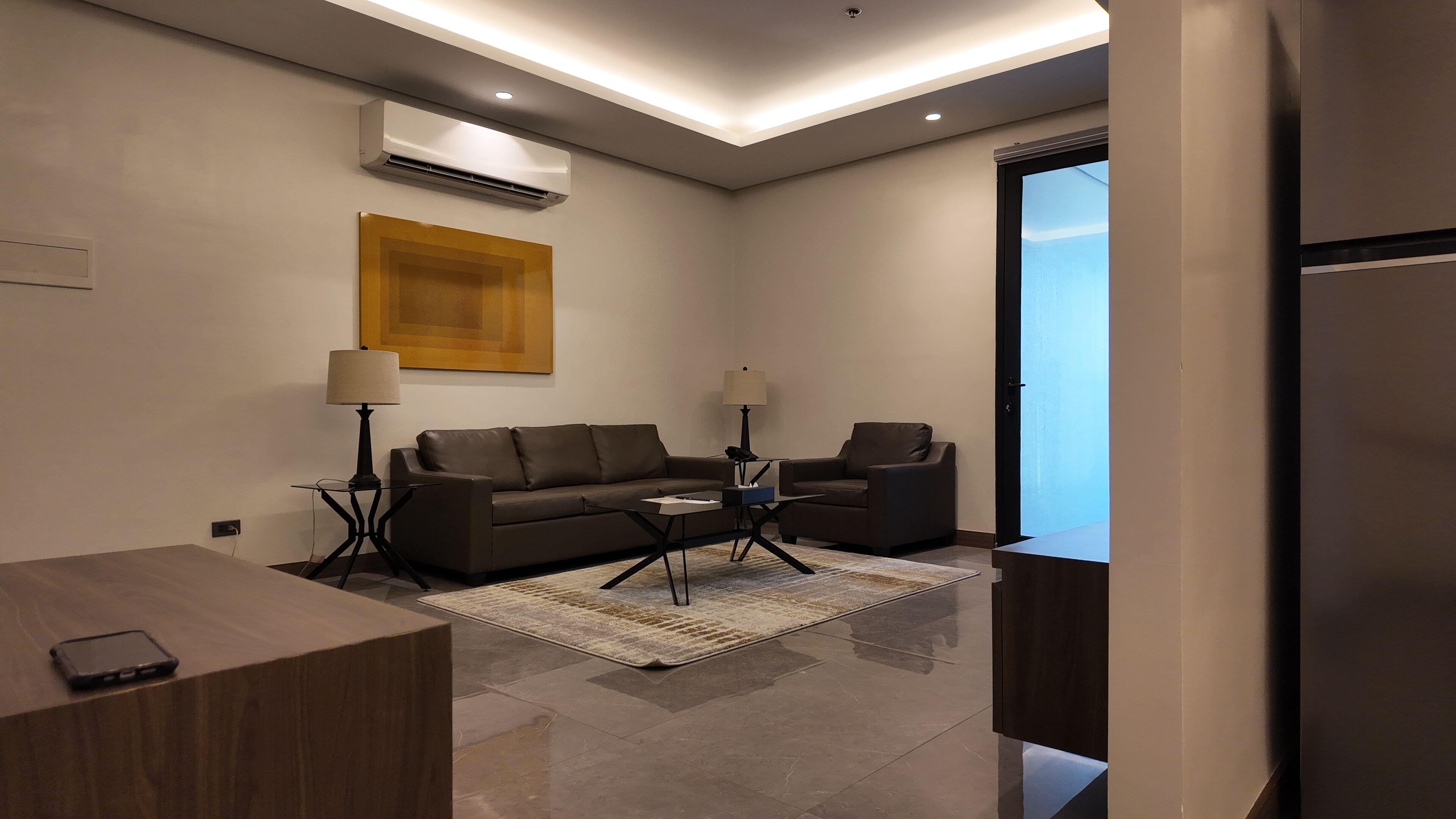 A modern living room with a sofa, two chairs, a coffee table, and a rug.