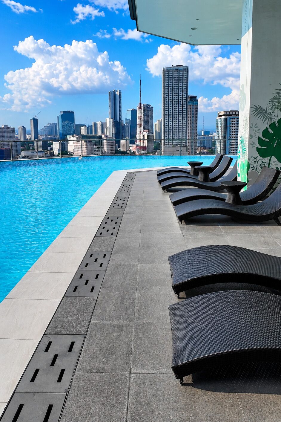 A rooftop pool with lounge chairs and a city skyline view.
