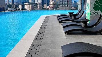 A rooftop pool with lounge chairs and a city skyline view.