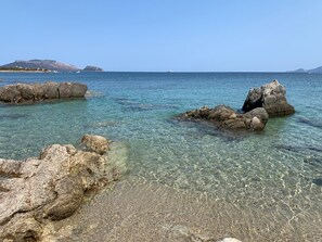 A clear coastal area with rocky formations and calm sea.