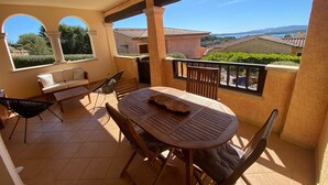 A balcony with a round wooden table, two chairs, a sofa, and a hammock. - La Terrazza Del Faro - Stunning 1 bedroom flat 600m from the beach (Pittulongu)
