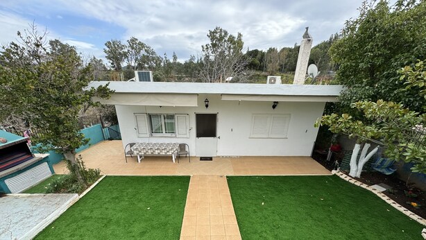 Una casa con un pequeño patio, una banca y vistas de los árboles circundantes.