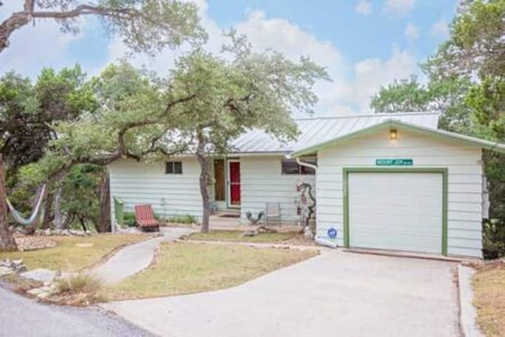 A single-story house with a green garage door, a red door, and a small porch.