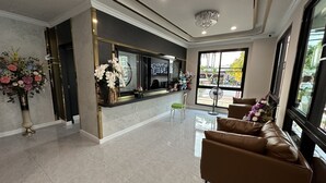 A modern reception area with a marble floor, a reception desk, a chandelier, and a large window offering a view of the outside.