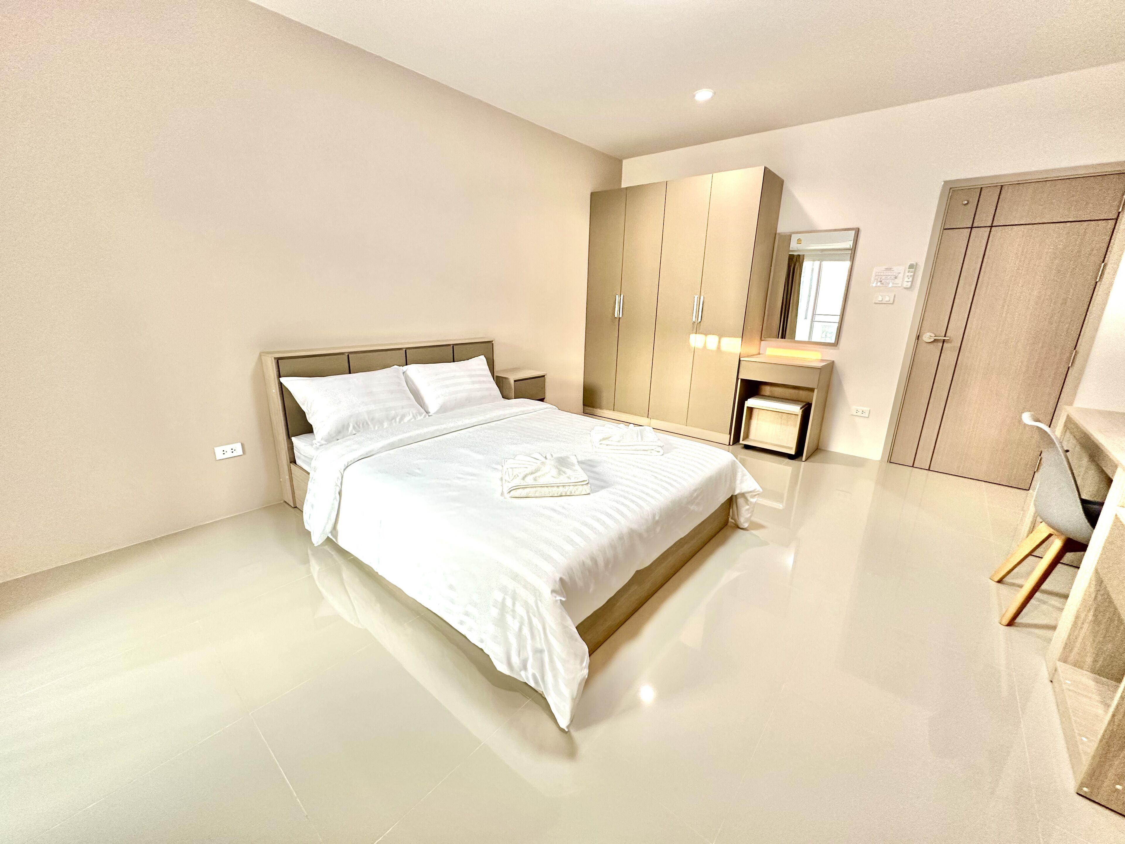 A modern bedroom with a large bed, a wardrobe, a bedside table, and a chair.