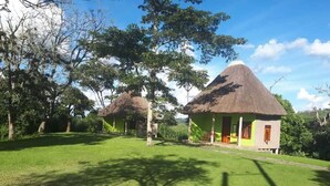 A rural setting with thatched-roof huts, a well-maintained lawn, and trees. - Lake Nkuruba Nature Reserve (Fort Portal)