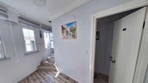 A hallway with a wooden floor, a staircase, and a door leading to another room. - ArkaDeniz Konukevi Bozcaada (Bozcaada)