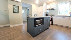 A modern kitchen with a central island, built-in microwave, and stainless steel appliances. - Newer Construction waterfront house with AC and WiFi in Barnstead (Barnstead)