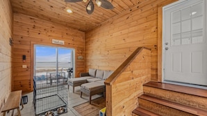 A wooden cabin interior with a sofa, a pet cage, and a staircase. - 5 Min to Lamoine State Park & Lamoine Beach (Lamoine)