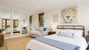 A bedroom with a large bed, a mirror, a painting of a lion, and a view through a glass door. - South Coast Hinterland Retreat on 30 acres with Rainforest Hikes and Firepit (Broughton Village)