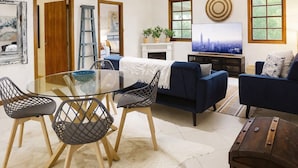 A spacious living area with a glass dining table, dark sofas, and a television. - South Coast Hinterland Retreat on 30 acres with Rainforest Hikes and Firepit (Broughton Village)