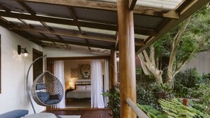 A wooden deck with a hanging chair, a bed with a lion mural, and a garden with ferns. - South Coast Hinterland Retreat on 30 acres with Rainforest Hikes and Firepit (Broughton Village)
