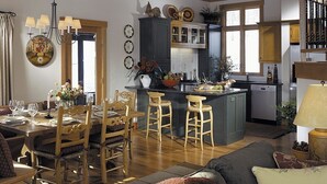 A spacious living area with a wooden dining table, bar stools, and a kitchen with a central island.