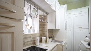 A modern kitchen with white cabinets, a built-in stove, and hanging utensils. - Charme & Chic Studio (Salerno)
