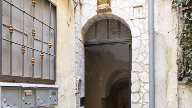 A narrow alleyway with a stone wall, a metal gate, and a door leading to an interior space. - Charme & Chic Studio (Salerno)