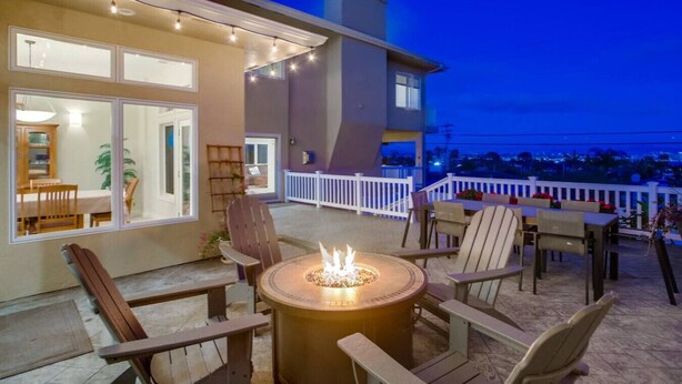 A patio with outdoor seating, a fire pit, and a view of the city at dusk.