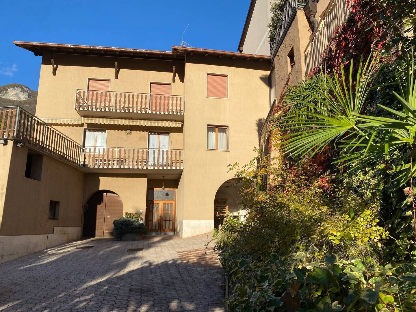 A building with a central entrance, two balconies, and a cobblestone courtyard.