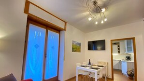 Un salon moderne comprenant un coin repas, une cuisine et un téléviseur fixé au mur.