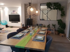 Enjoy meals in this stylish dining area with a long table, stone accent wall, and potted plants.