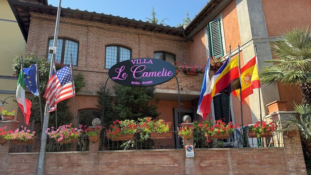 Un edificio con un cartel que dice 'Villa Le Camelie' y varias banderas.