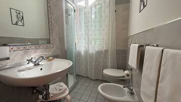 A bathroom with a sink, bidet, toilet, and shower area.