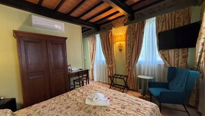 Una habitación de hotel con cama, escritorio, silla, televisor y armario.