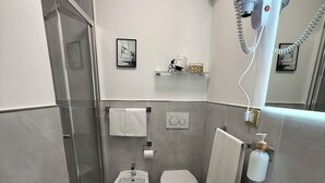 Un baño moderno con cabina de ducha de vidrio, un bidé, un inodoro y un lavabo.