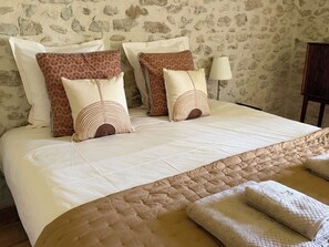 A neatly made bed with a quilted headboard, multiple pillows, and a bedside lamp.