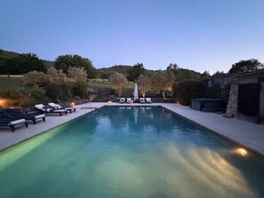 Ein rechteckiger Pool mit Liegestühlen und einer Steinmauer an einer Seite.