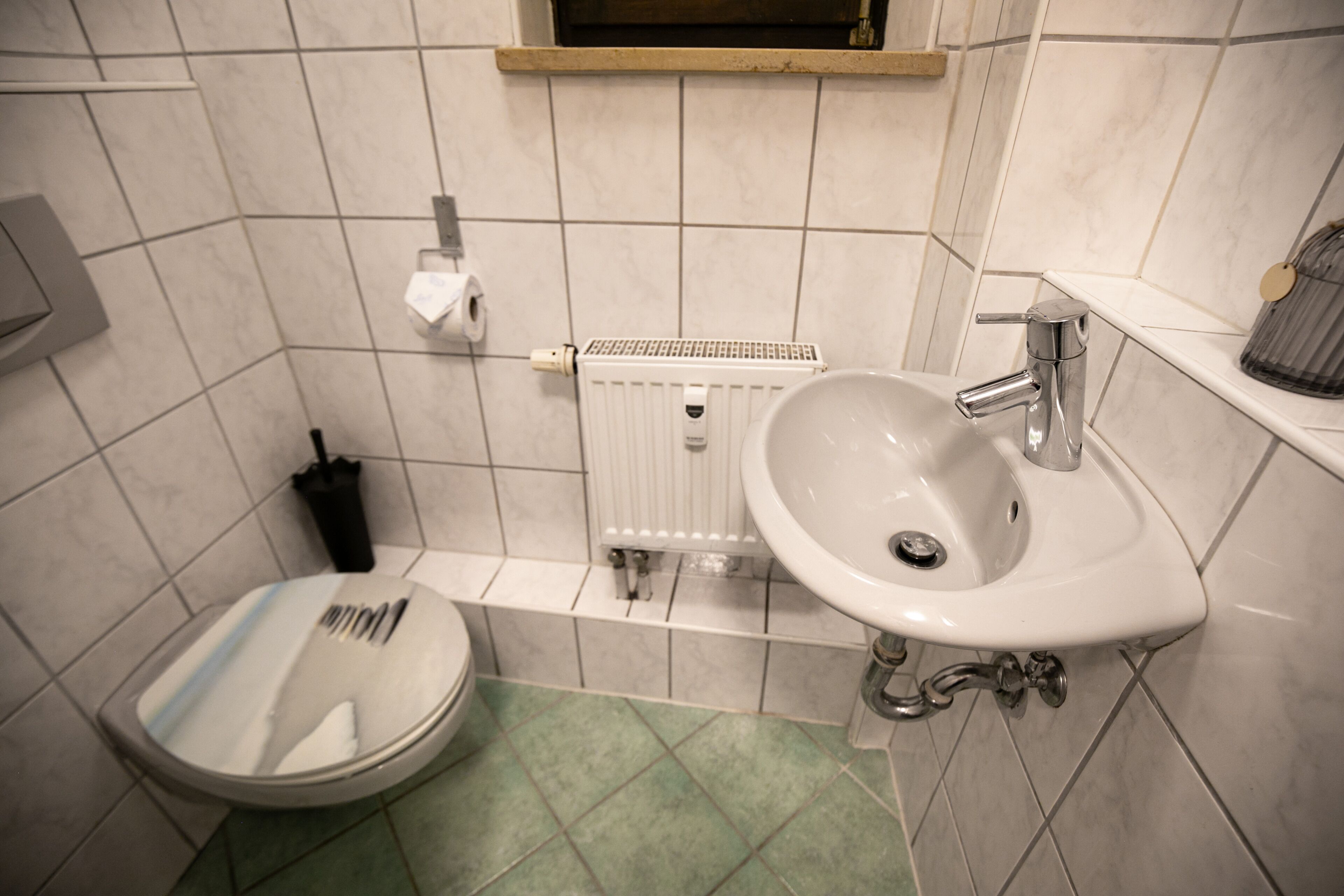 A bathroom with a white sink, a toilet, and a radiator.